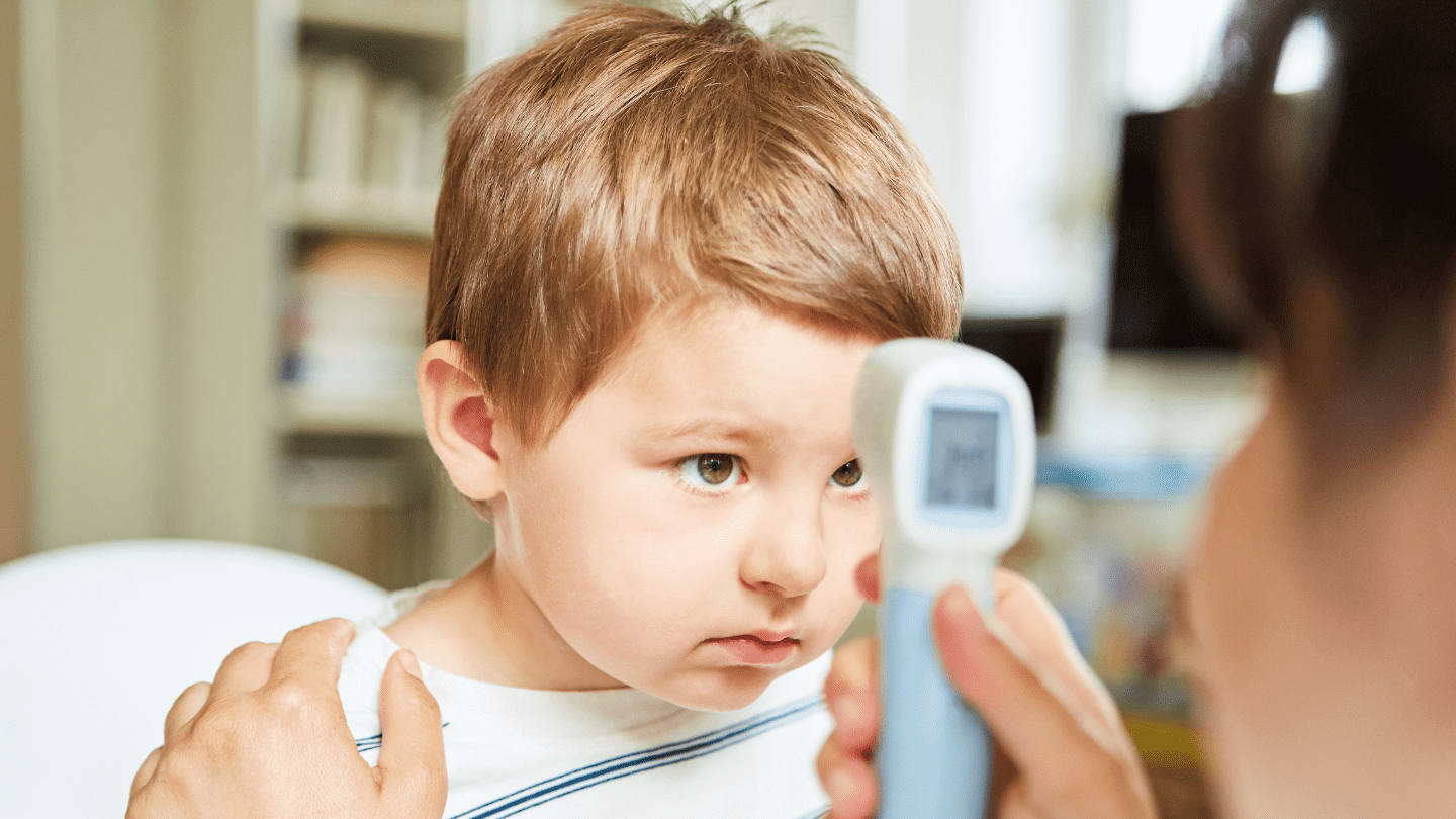 Child having forehead temperature checked with a non-contact infrared thermometer.